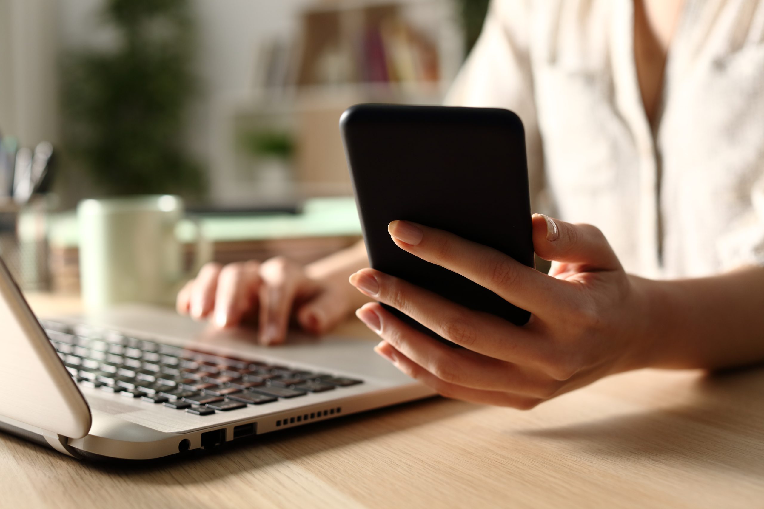 women holding a cell phone and looking at Medicare plans on a laptop